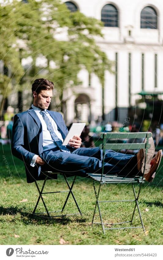 Geschäftsmann in Manhattan sitzt auf Gartenstuhl und benutzt digitales Tablet mit hochgeklappten Füßen lesen Lektüre Tablet Computer Tablet-PC Tablet PC iPad