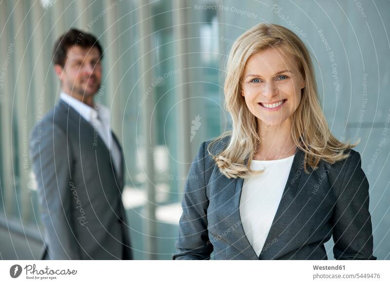 Porträt einer lächelnden Geschäftsfrau mit ihrem Partner im Hintergrund Portrait Porträts Portraits Geschäftsfrauen Businesswomen Businessfrauen Businesswoman