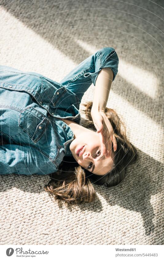 Porträt einer jungen Frau, die auf einem Teppich liegt und das Sonnenlicht genießt Portrait Porträts Portraits Teppiche weiblich Frauen Erwachsener erwachsen