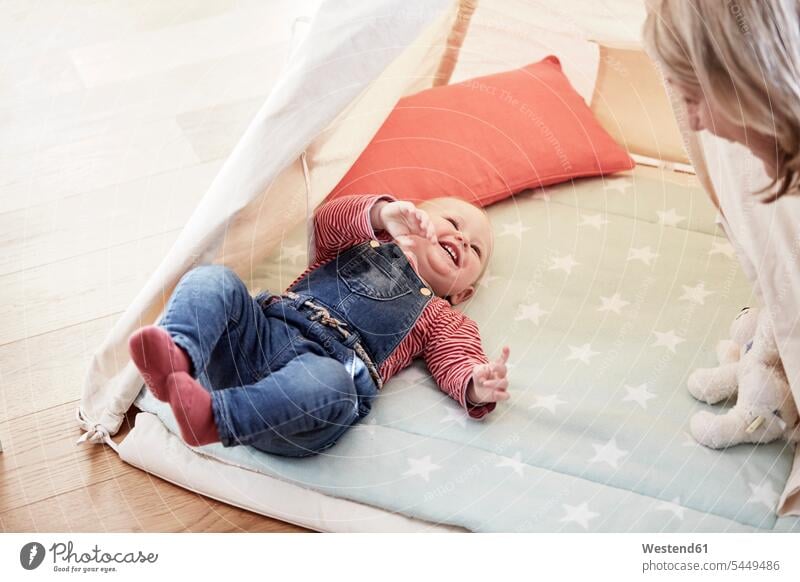 Glückliches kleines Mädchen liegt auf einer Decke und sieht die Großmutter an Baby Babies Babys Säuglinge Kind Kinder lachen Grossmutter Oma Grossmama