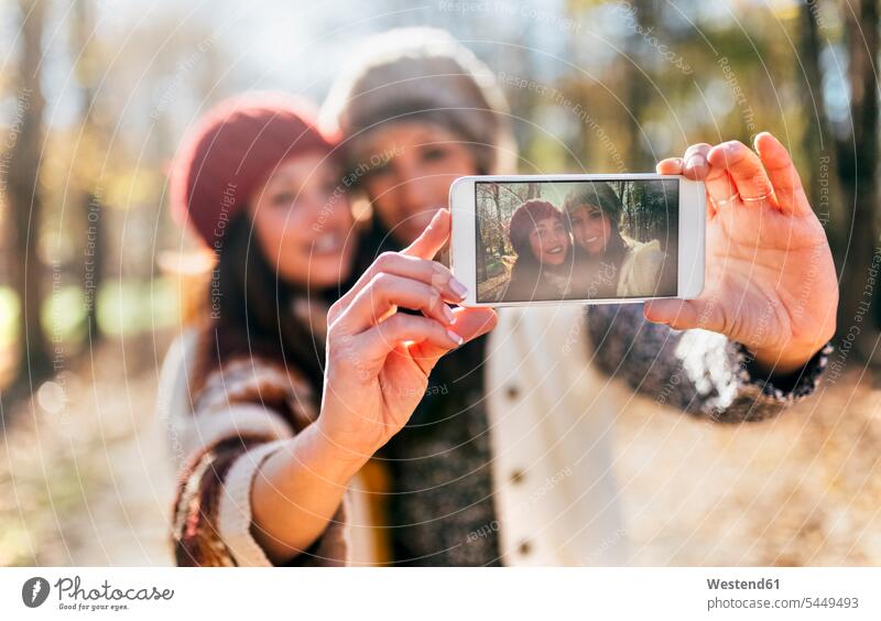 Zwei hübsche Frauen machen ein Selfie in einem herbstlichen Wald Forst Wälder Smartphone iPhone Smartphones Selfies Herbst Freundinnen weiblich schön Handy