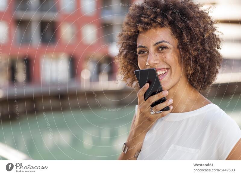 Junge Frau mit Smartphone weiblich Frauen Locken lockiges Haar gelockt gelocktes Haar glücklich Glück glücklich sein glücklichsein Sprachnachricht