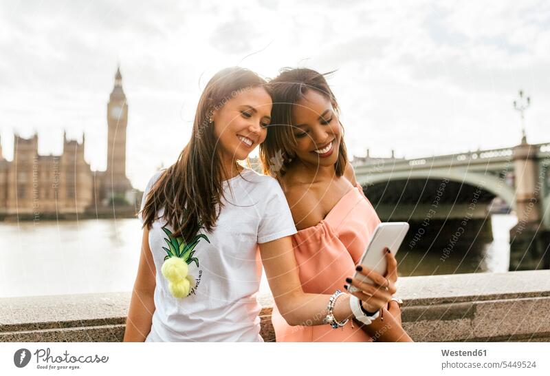 UK, London, zwei schöne Frauen machen ein Selfie in der Nähe der Westminster Bridge Freundinnen Selfies Handy Mobiltelefon Handies Handys Mobiltelefone lächeln