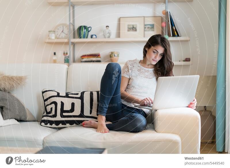 Frau sitzt zu Hause auf der Couch mit Laptop Sofa Couches Liege Sofas Notebook Laptops Notebooks weiblich Frauen Computer Rechner Erwachsener erwachsen Mensch