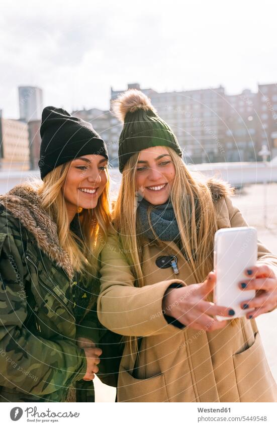 Zwei Freunde machen ein Selfie mit Smartphone Kameradschaft Freundin Selfies Mützen Handies Handys Mobiltelefon Mobiltelefone iPhone Smartphones Leute Menschen