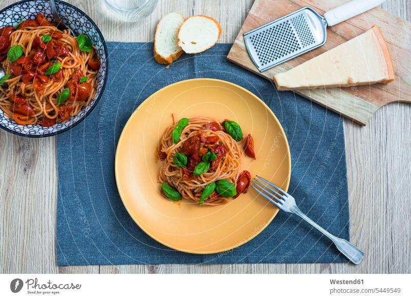 Spaghetti mit Kirschtomaten und Basilikum auf einem Teller zubereitet Parmesan angerichtet garniert Italienische Küche servierfertig Käsereibe Kaesereibe Reibe