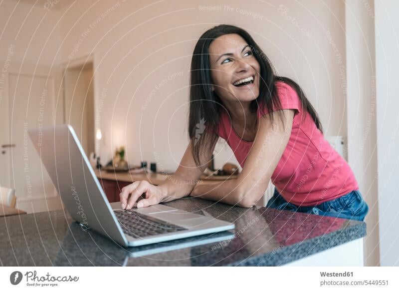 Glückliche Frau benutzt Laptop zu Hause Notebook Laptops Notebooks weiblich Frauen lachen Computer Rechner Erwachsener erwachsen Mensch Menschen Leute People