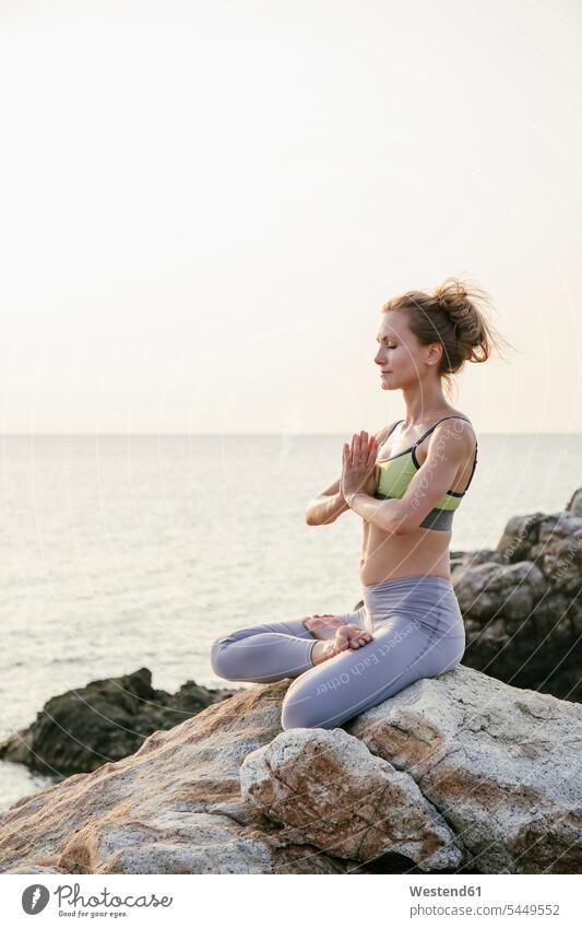 Frau sitzt im Lotussitz und meditiert am Strand üben ausüben Übung trainieren weiblich Frauen Yoga Retreat Urlaub Ferien Yoga-Übungen Yogauebungen Yogaübungen