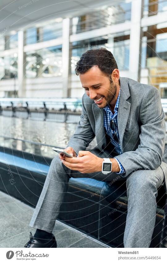Lächelnder Geschäftsmann, der mit seinem Smartphone in der Stadt Nachrichten verschickt lächeln Handy Mobiltelefon Handies Handys Mobiltelefone Businessmann