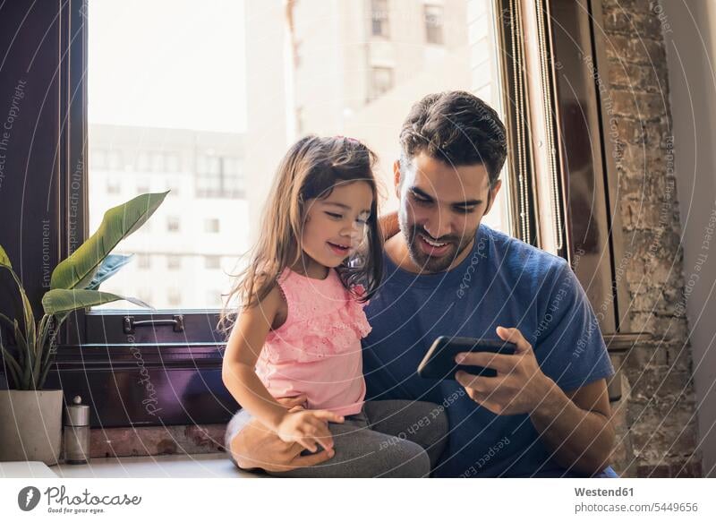 Vater mit Tochter benutzt Smartphone in der Küche Papas Väter Vati Vatis Papis iPhone Smartphones Töchter Zuhause zu Hause daheim Eltern Familie Familien Mensch