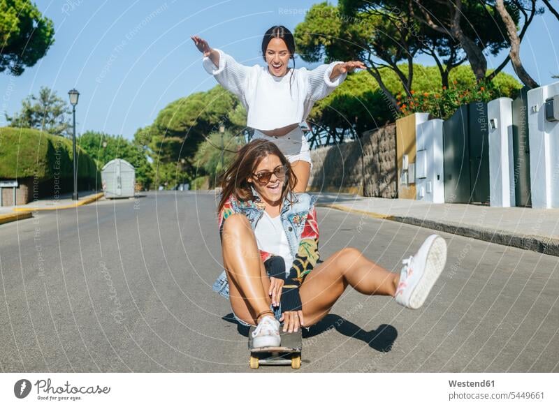Zwei lachende Freunde zusammen auf dem Skateboard Freundinnen Rollbretter Skateboards Gemeinsam Zusammen Miteinander Straße Strassen Straßen Freundschaft