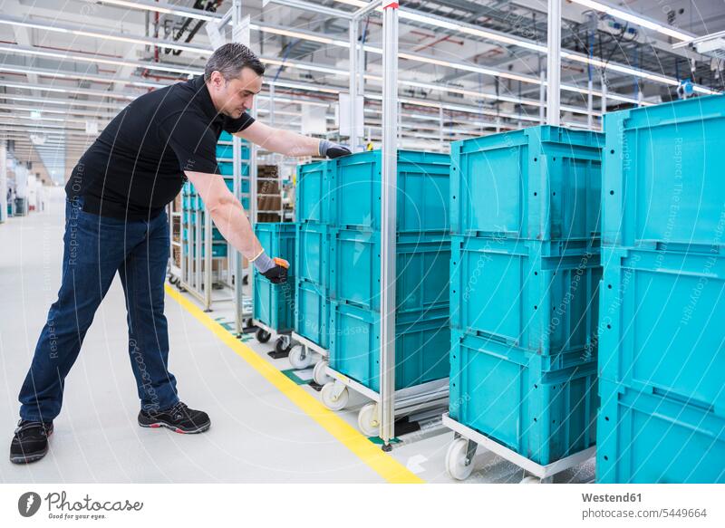Mann scannt Kartons auf Schlepperzug in Industriehalle Kiste Kisten arbeiten Arbeit Männer männlich Fabrik Fabriken Erwachsener erwachsen Mensch Menschen Leute