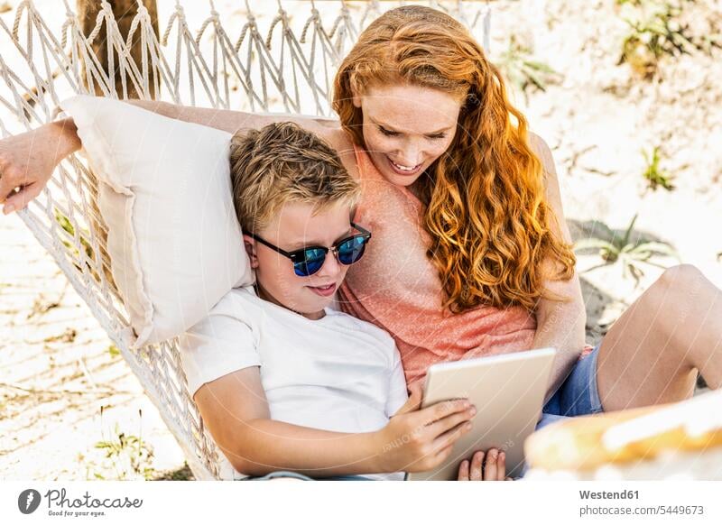 Glückliche Mutter und Sohn liegen in der Hängematte und schauen auf das Tablett entspannt entspanntheit relaxt Söhne Tablet Computer Tablet-PC Tablet PC iPad