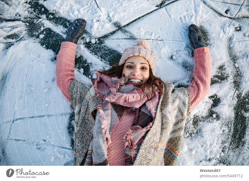 Porträt einer glücklichen Frau, die auf dem gefrorenen See liegt Wollmütze Wollmützen Strickmütze Strickmützen liegen liegend lächeln weiblich Frauen Mütze