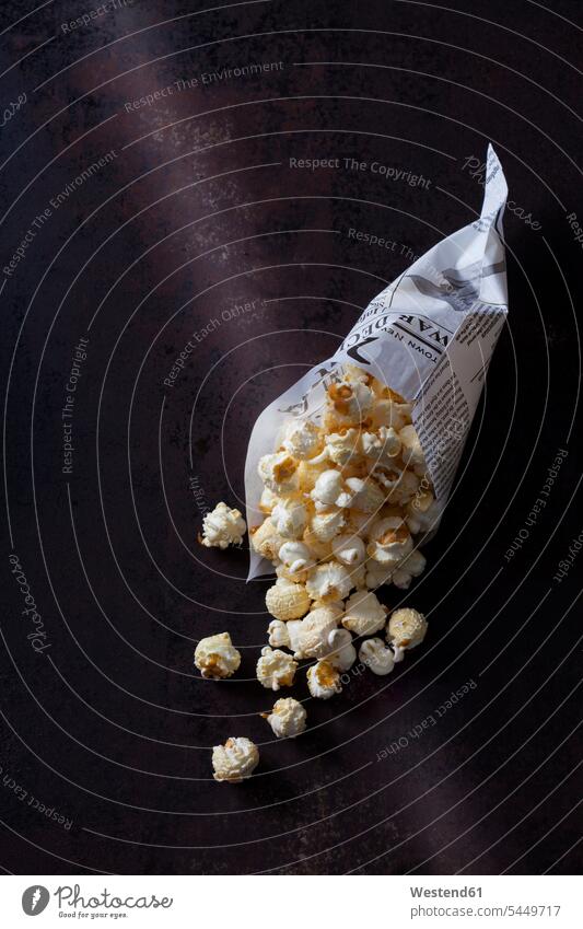 Papiertüte mit Popcorn auf rostigem Hintergrund Draufsicht Vogelperspektive von oben Aufsicht Puffmais Nahaufnahme Nahaufnahmen Großaufnahme close up close-up