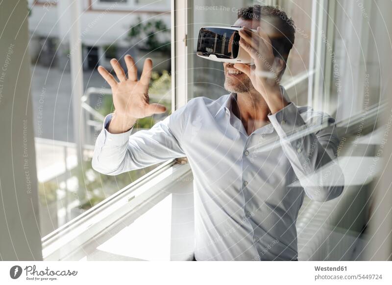 Geschäftsmann am Fenster mit VR-Brille Virtual Reality Virtuelle Realität Businessmann Businessmänner Geschäftsmänner Büro Office Büros Geschäftsleute