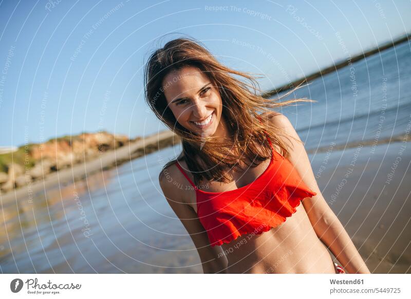 Porträt einer glücklichen jungen Frau am Strand Portrait Porträts Portraits Beach Straende Strände Beaches weiblich Frauen Erwachsener erwachsen Mensch Menschen