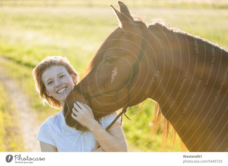 Porträt einer glücklichen jungen Frau mit Pferd im Gegenlicht weiblich Frauen Equus caballus Pferde Erwachsener erwachsen Mensch Menschen Leute People Personen