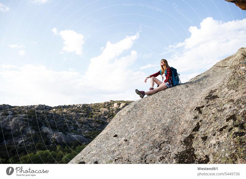 Spanien, Madrid, junge Frau ruht sich während eines Trekking-Tages auf einem Felsen aus sitzen sitzend sitzt wandern Wanderung Berg Berge weiblich Frauen