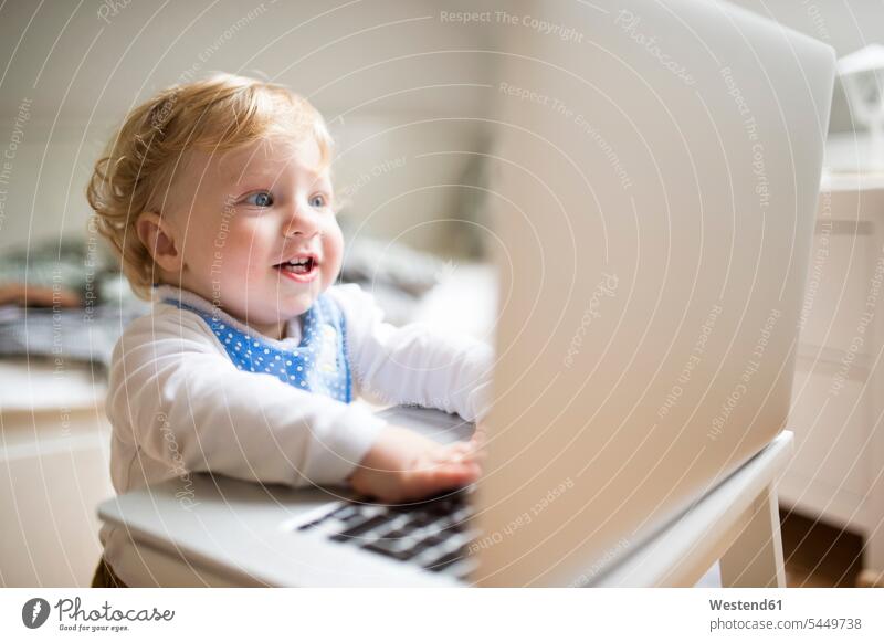 Kleiner Junge spielt zu Hause mit Laptop spielen Notebook Laptops Notebooks Computer Rechner Zuhause daheim lächeln blond blonde Haare blondes Haar neugierig