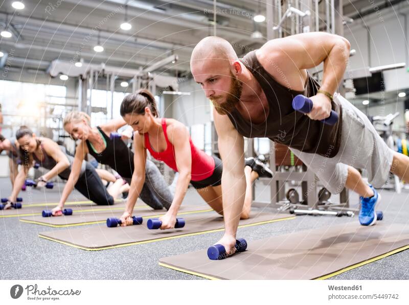 Gruppe von Sportlern, die mit Hanteln im Fitnessstudio trainieren Fitnessclubs Fitnessstudios Turnhalle Liegestützen Push-Up Pushups Push-Ups fit Gesundheit