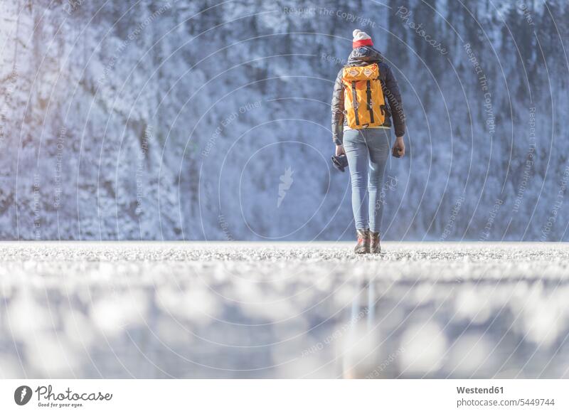 Deutschland, Berchtesgadener Land, Rückenansicht einer Frau mit Rucksack beim Spaziergang auf dem zugefrorenen Königssee Winter winterlich Winterzeit weiblich