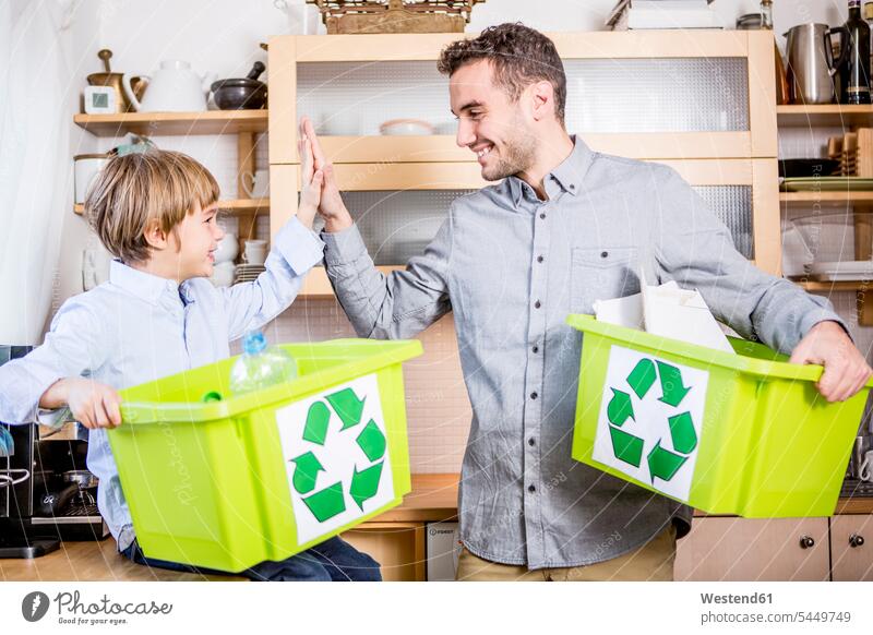 Vater und Sohn zu Hause mit Abfallboxen Familie Familien Recycling Ökologie Wiederverwertung recyceln Söhne lächeln Zuhause daheim Papas Väter Vati Vatis Papis