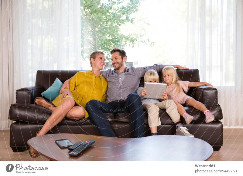 Familie sitzt zu Hause auf der Couch mit Tablette sitzen sitzend Familien benutzen Zuhause daheim Tablet Computer Tablet-PC Tablet PC iPad Tablet-Computer Sofa