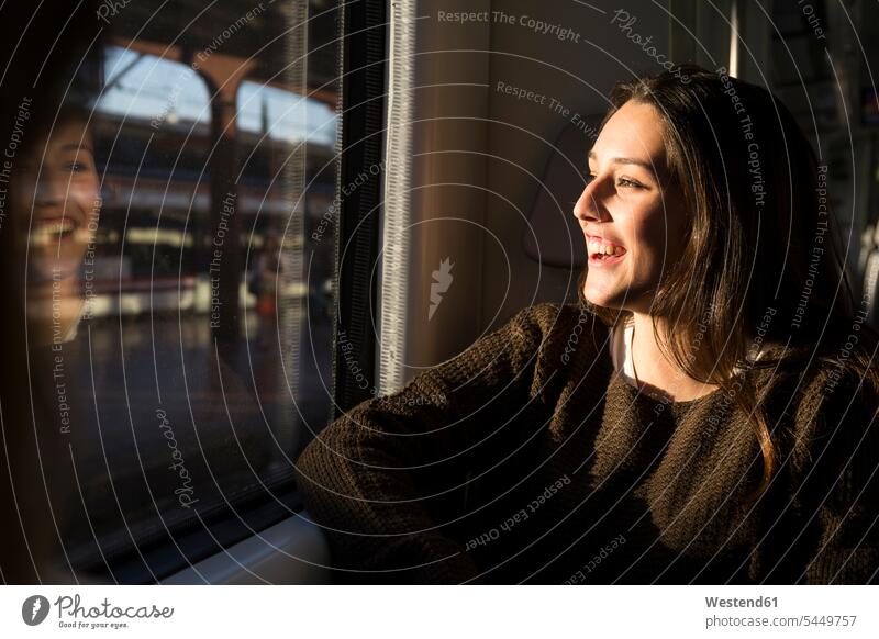 Glückliche junge Frau im Zug, die aus dem Fenster schaut Bahnen Züge weiblich Frauen Verkehrswesen Transportwesen Erwachsener erwachsen Mensch Menschen Leute