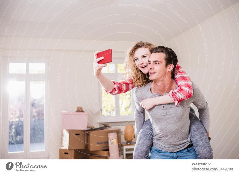 Glückliches junges Paar im neuen Haus, das ein Selfie macht Wohnung wohnen Wohnungen Handy Mobiltelefon Handies Handys Mobiltelefone Spaß Spass Späße spassig