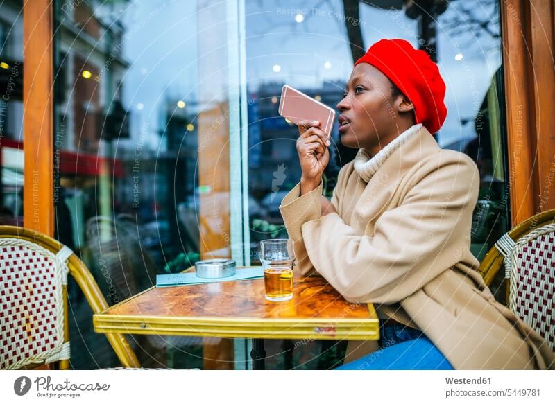 Junge Frau in Paris sitzt in einem Café und hinterlässt eine Sprachnachricht weiblich Frauen Cafe Kaffeehaus Bistro Cafes Cafés Kaffeehäuser sitzen sitzend
