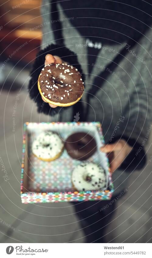 Frau hält einen Doughnut mit Schokoladenglasur, Teilansicht Donut Donuts Doughnuts halten Gebäck Backware Gebaeck Backwaren Süßspeise Süsses Süßes süß