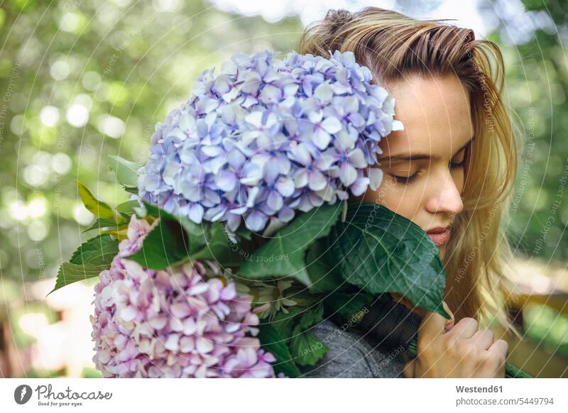 Junge Frau mit geschlossenen Augen hält einen Strauß Hortensien Blumenstrauß Bouquet Blumenstrauss Blumensträusse Blumensträuße Blüte halten Hydrangea weiblich