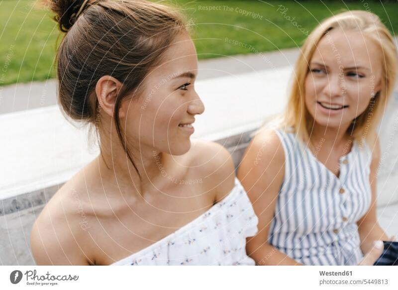 Zwei lächelnde junge Frauen unterhalten sich im Freien Freundinnen sprechen reden weiblich glücklich Glück glücklich sein glücklichsein Freunde Freundschaft
