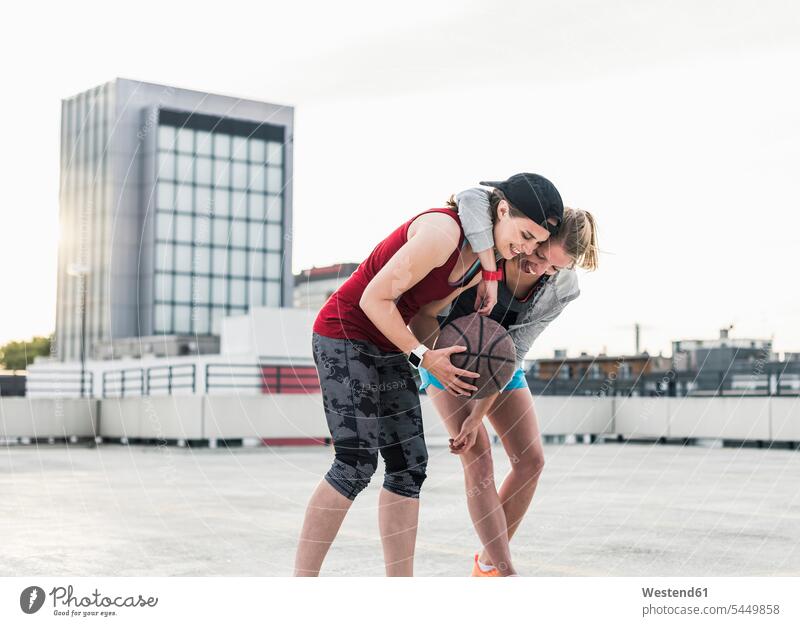 Zwei glückliche Frauen mit Basketball auf Parkebene in der Stadt Basketbaelle Basketbälle umarmen Umarmung Umarmungen Arm umlegen lächeln weiblich Freundinnen