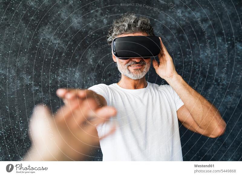 Reifer Mann mit VR-Brille, der die Hände ausstreckt T-Shirt T-Shirts ausstrecken Digitalisierung interaktiv Interaktivität Wearable Wearables Wearable Computer