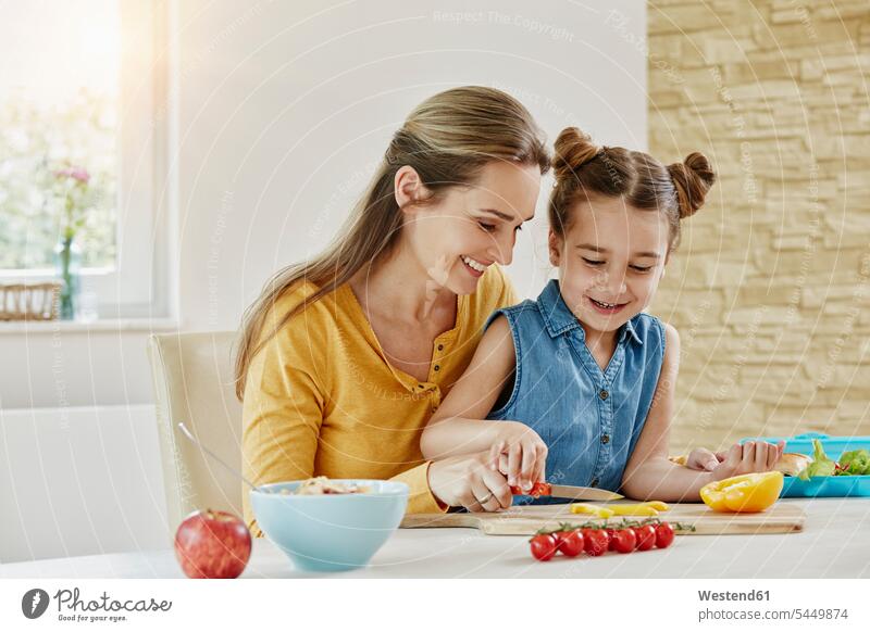 Glückliche Mutter mit Tochter zu Hause beim Gemüseschneiden Gemuese lächeln glücklich glücklich sein glücklichsein Töchter Mami Mutti Mütter Mama Essen Food