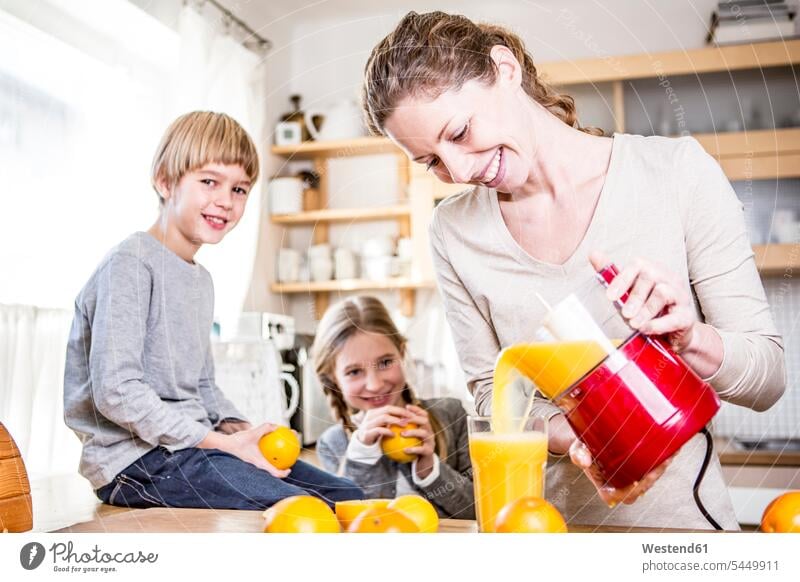 Frau gießt frisch gepressten Orangensaft in Glas für Kinder Küche Küchen Saft Saefte Säfte Getränk Getraenk Getränke Getraenke Food and Drink Lebensmittel