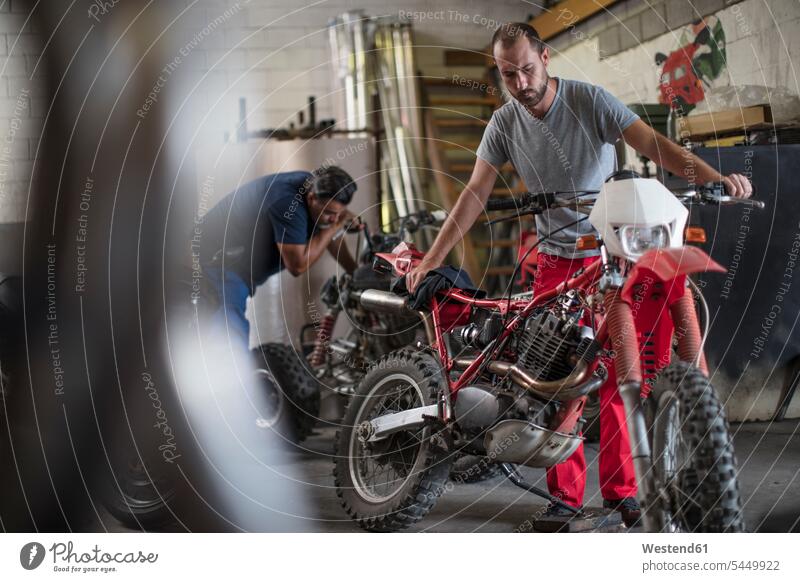 Zwei Mechaniker in Motorradwerkstatt arbeiten Arbeit Monteur Motorräder reparieren Reparatur Industrie industriell Gewerbe Industrien Kraftfahrzeug