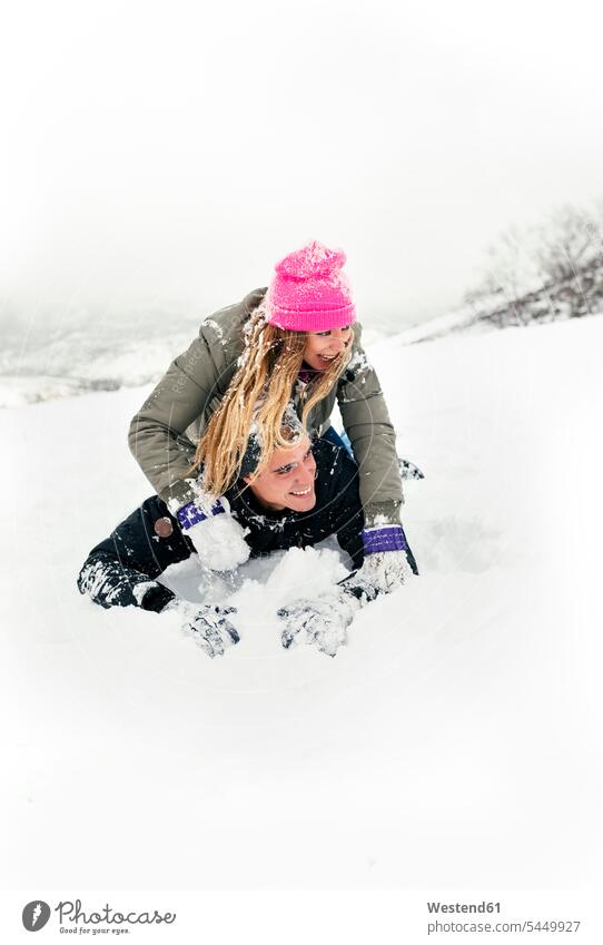 Junges Paar amüsiert sich im Schnee spielen lachen Winter winterlich Winterzeit Schneeballschlacht Schneeballschlachten Pärchen Paare Partnerschaft positiv