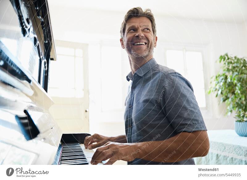 Reifer Mann spielt zu Hause Klavier Spaß Spass Späße spassig Spässe spaßig üben ausüben Übung trainieren fröhlich Fröhlichkeit Frohsinn Heiterkeit spielen Piano