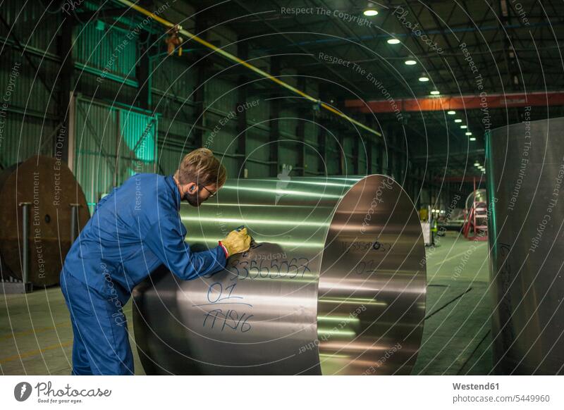 Arbeiter beschriftet Metall in der Fabrik Fabriken Mann Männer männlich schreiben aufschreiben notieren schreibend Schrift arbeiten Fabrikgebäude Fabrikgebaeude
