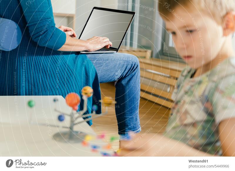 Junge erkundet Sonnensystemmodell mit Frau mit Laptop im Kindergarten Modell Erzieherin lernen Pädagogik Mensch Bildung Wissen Digital Beruf