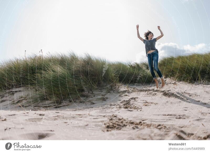 Glückliche Frau springt in Stranddüne Beach Straende Strände Beaches lachen weiblich Frauen springen hüpfen Sanddüne Sanddünen positiv Emotion Gefühl Empfindung