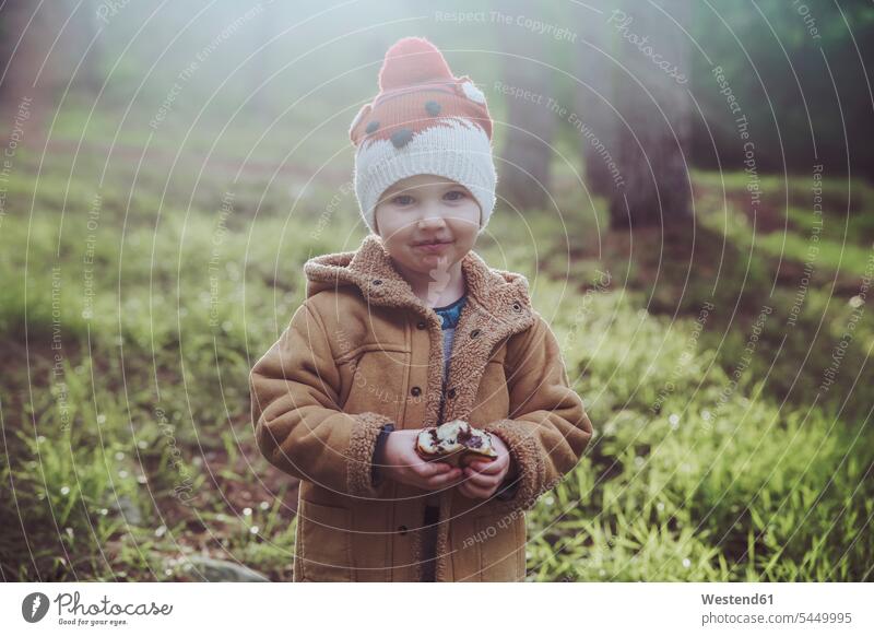 Porträt eines Jungen, der Berliner im Wald isst Wollmütze Wollmützen Strickmütze Strickmützen lächeln eine Person single 1 ein Mensch einzelne Person Ein