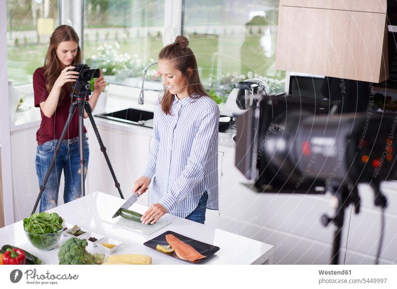 Frau nimmt ihre Freundin beim Schneiden einer Zucchini auf Fotokamera Kamera Kameras Leute Menschen People Person Personen erwachsen Erwachsene Frauen weiblich