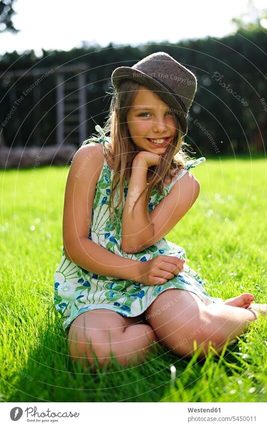 Lächelndes Mädchen mit Hut im Garten sitzend weiblich lächeln Hüte Gärten Gaerten Spaß Spass Späße spassig Spässe spaßig sitzt Kind Kinder Kids Mensch Menschen