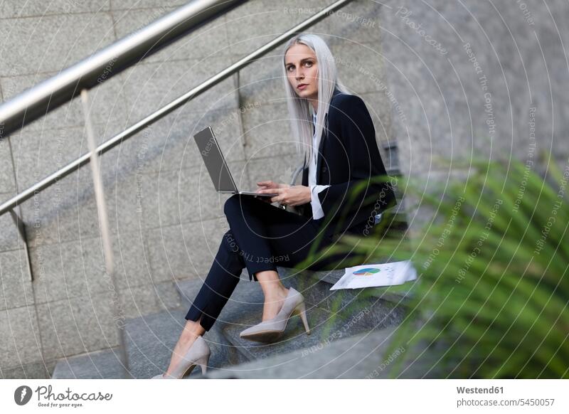 Junge Geschäftsfrau, die in der Stadt auf einer Treppe sitzt und einen Laptop benutzt Notebook Laptops Notebooks Frau weiblich Frauen Geschäftsfrauen
