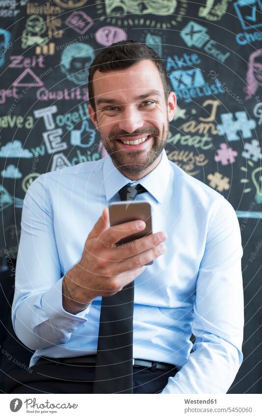 Porträt eines lächelnden Geschäftsmannes mit Handy im Kreativbüro Businessmann Businessmänner Geschäftsmänner Mobiltelefon Handies Handys Mobiltelefone Portrait