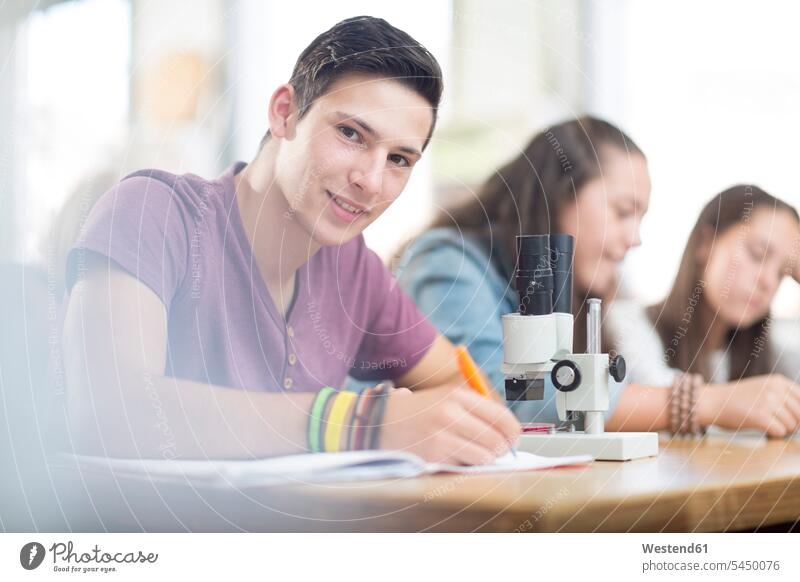 Porträt eines lächelnden Wissenschaftsstudenten im Unterricht schreiben lernen Mikroskop Schüler Bildung Schule aufschreiben Vorderansicht Freude Gruppe